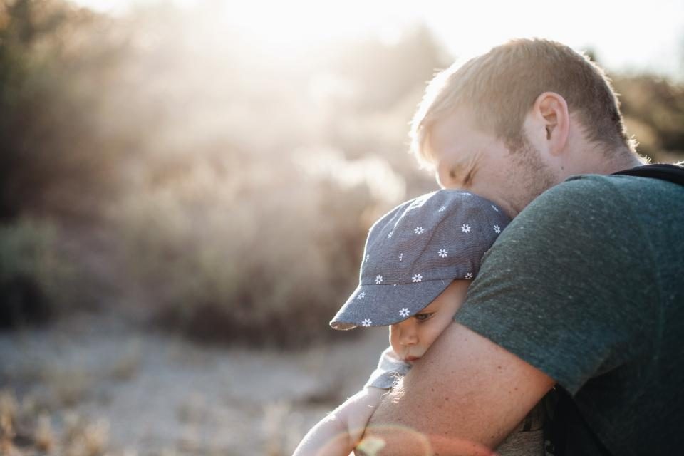 A dad hugging his young son outdoors