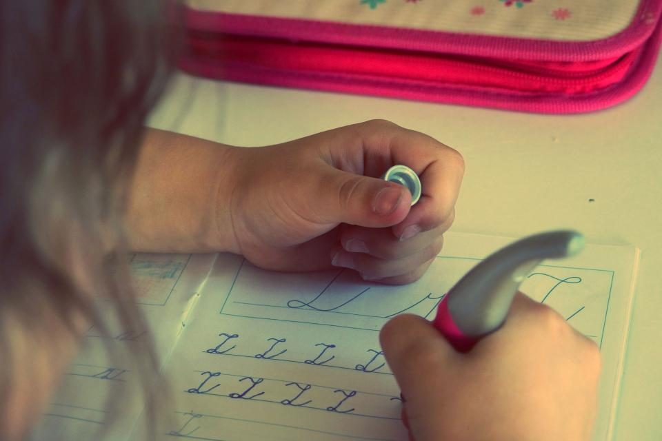 A child’s hands practicing letters on a worksheet